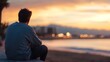 © Generative AI - Thoughtful young man gazing at the sunset by the beach with city skyline in the background : Generative AI