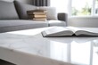 © Selvi - Open Book Rests on Marble Table in Sunlit Room, Near Cozy Sofa and Stack of Books.