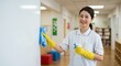 © IbragimovN - Smiling asian woman cleaning classroom whiteboard with spray and cloth in school environment