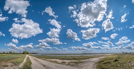 Wall Mural - Rural dirt road forks, sunny sky, lake background, travel