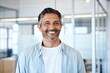 © NISHAN'S STUDIO - Close-up Headshot of a Confident Middle-Aged Indian or Latin Business Leader, CEO, or Professional Man, Smiling Against a Blurred Office Background
