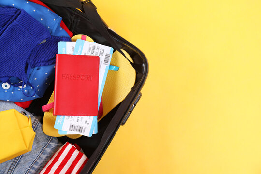 Wall Mural -  - travel abroad. packed suitcase, passport and tickets on yellow background, top view. space for text