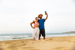 © Westend61 - Couple taking selfie and standing at beach