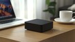 © pakbar - Black square device on wooden desk near laptop and coffee cup.