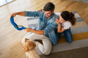 Wall Mural - Cute dog enjoys love from owners at home. Couple pets and cares for furry friend, creating a bond.