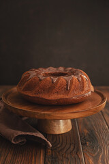 Wall Mural - Chocolate cake with chocolate icing on dark wooden table. Low key. Front view