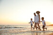 © New Africa - Happy family running on sandy beach near sea at sunset