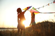© New Africa - Little children playing with kites outdoors at sunset. Spending time in nature