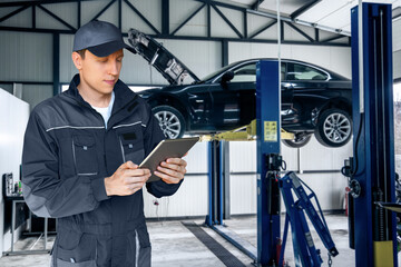 Poster - Serviceman with digital tablet on the background of the car in the car service.