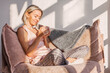 © Tatyana Gladskih - Happy dreamy middle aged woman sitting on sofa in living room with cup of tea or coffee