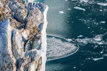 Calving at the front terminus of Hisinger Glacier, Dickson fjord, Northeast Greenland National Park. As the glacier advances, large chunks of ice break away and fall into the water.