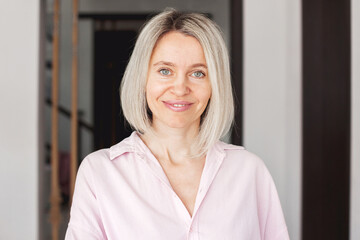 Wall Mural - Smiling middle aged mature woman looking at camera at home