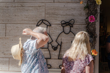 People look at the wall decoration where a boy and a girl are holding hands.