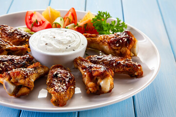 Wall Mural - Honey chicken wings with sesame and white sauce on wooden table