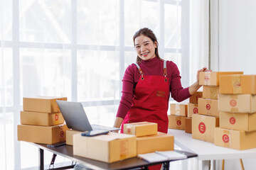 Wall Mural - Portrait of Asian young woman SME working with a box at workplace. start-up small business owner, small business entrepreneur SME or freelance business online and delivery concept.
