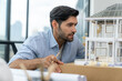 © Summit Art Creations - Closeup portrait of smart caucasian architect engineer inspect house model while thinking about building construction at architect studio on table with project plan, blueprint, equipment. Tracery.