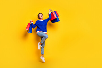 Wall Mural - Full length photo of funky cute lady dressed knitted sweater rising shoppers jumping high empty space isolated yellow color background