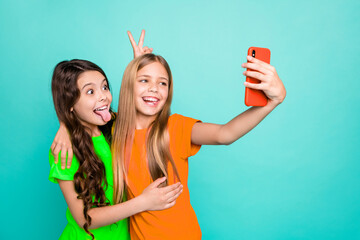 Photo of two cute excited nice brunette funky funny blonde model trendy people girls wearing pink yellow t-shirts recording video call while isolated with teal background