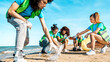 © charmedlightph - Group of eco volunteers picking up plastic trash on the beach - Activist people collecting garbage protecting the planet - Ocean pollution, environmental conservation and ecology concept.