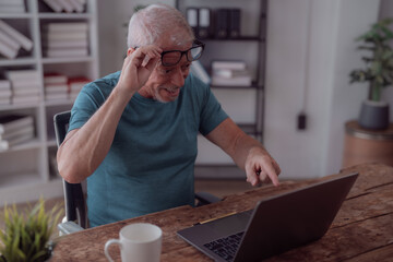 surprised senior man adjusting his glasses and pointing at laptop screen while working from home in 