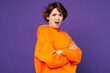 © ViDi Studio - Side view young sad frowning mad indignant upset Caucasian woman she wear orange hoody casual clothes hold hands crossed folded isolated on plain purple background studio portrait. Lifestyle concept.