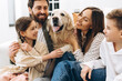 © Maria Vitkovska - Happy family embracing golden retriever at home