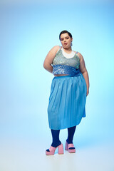 Wall Mural - Confident young plus size woman showcasing vibrant fashion under soft blue light