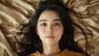 © BOJOShop - Portrait of a Young Asian Woman with Long Black Hair Lying on Gold Fabric