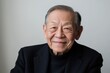 © Surachetsh - An elderly Asian man with gentle smile stands against solid gray background, embodying inner peace, happiness. His calm expression, relaxed posture capture naturally serene moment.