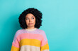 © deagreez - Young stylish woman with curly hair expressing a thoughtful attitude against turquoise background