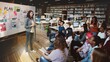 © Rawpixel.com - A diverse group of students in a library listens to a female teacher presenting a plan on a board. The library setting is filled with books and computers. Teacher teaching high school class.