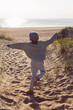 © saulich84 - A fashionable seven-year-old boy runs along a sandy beach by the sea in autumn in a sweater and hat at sunset.