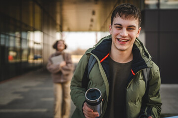 Wall Mural - man walk outdoor with backpack while drink coffee from thermos