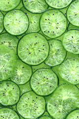 Canvas Print - A vibrant green background of translucent kiwi fruit slices, speckled with tiny black seeds and glistening juice.