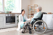 © Pixel-Shot - Physical therapist with senior woman in wheelchair holding hands at home
