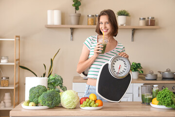 Wall Mural - Beautiful young happy woman with scales, healthy green smoothie, different vegetables and fruits in kitchen. Diet concept