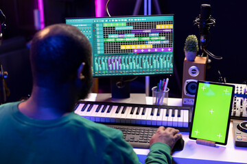 Fototapete - Artist producer creating new music with mix and master techniques, using a screen with copyspace layout. Skilled audio engineer editing tracks in post production, digital audio software.