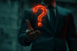 © Abul - Businessman Holding Glowing Red Question Mark Particle Effect On Dark Background