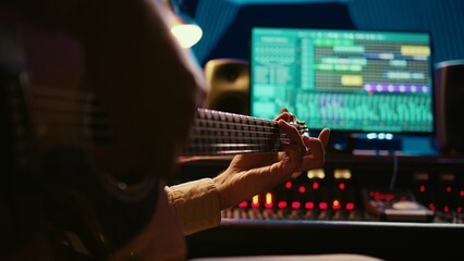 Leinwandbilder - Skilled artist guitarist recording a new song with electro acoustic guitar, composing and editing music in professional studio control room. Young musician songwriter creating tunes. Camera A.