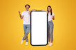 © Prostock-studio - Yes. Excited Couple Leaning On Big Smartphone With Empty White Screen Shaking Clenched Fists, Cheerful Guy And Lady Celebrating Win, Standing On Yellow Background, Mock Up Collage, Full Body Length