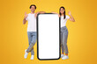 © Prostock-studio - Excited Casual Couple Leaning On Big Smartphone With White Empty Screen Showing Okay Sign Gesture, Cheerful Guy And Lady Recommending New App Or Website, Standing At Orange Wall, Mock Up, Full Body