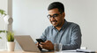 © Postmodern Studio - A man is sitting at a desk with a laptop and a cell phone