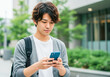 © TYAK_FACTORY - 街中で情報の検索をする若い男性