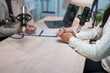 © Phimwilai - Two radio presenters engaging in an audio podcast recording session in a studio, seated at a wooden table equipped with microphones, a laptop, a clipboard, and a pen