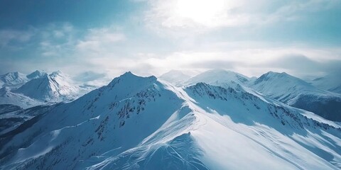 Wall Mural - Majestic snow-covered mountain peaks under a bright sun with a clear blue sky and soft clouds surrounding the serene landscape.
