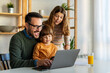 © NDABCREATIVITY - Happy family with kids having fun using laptop together, parent and children relaxing at home
