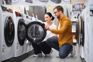 Wall Mural - Couple choosing wasing machine at electronics store