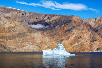 Wall Mural - a blue iceberg in the waters of dickson fjord, northeast greenland national park. low cloud hangs in