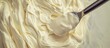 © StockKing - Smooth creamy texture of light beige spread with a silver spatula gliding over, creating soft waves in the surface composition.