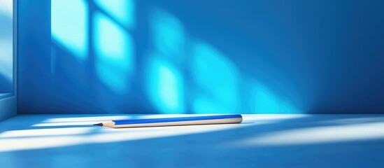 Fototapete - Minimalistic workspace with a blue background, sunlight casting shadows on the floor, featuring a notebook lying at the bottom center.
